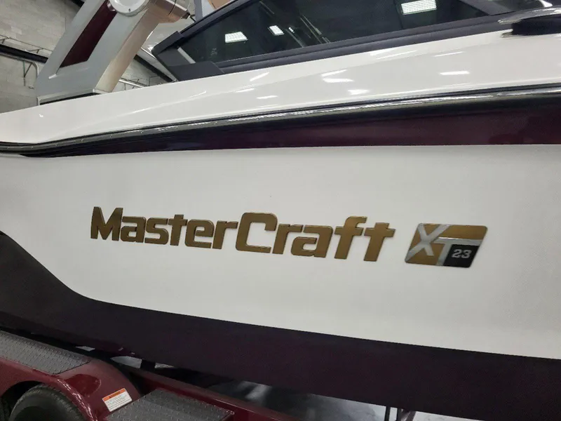 Slide: The Image of 2022 MasterCraft XT23 boat side view with logo in a showroom. - 32