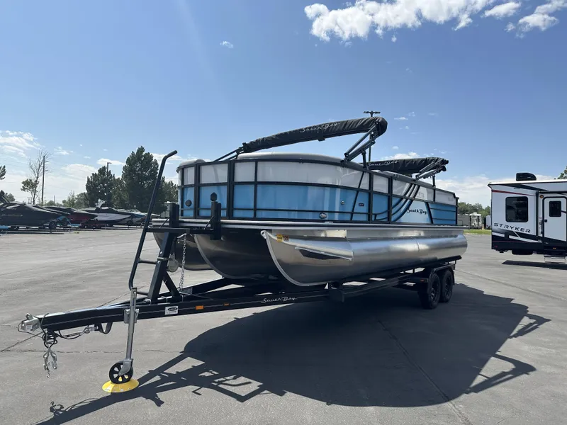 Slide: The Image of 2023 Forest River SOUTH BAY 224FCR pontoon boat on trailer under clear sky. - 1