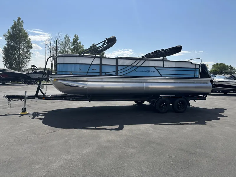 Slide: The Image of 2023 Forest River SOUTH BAY 224FCR pontoon boat on trailer, parked outdoors. - 2