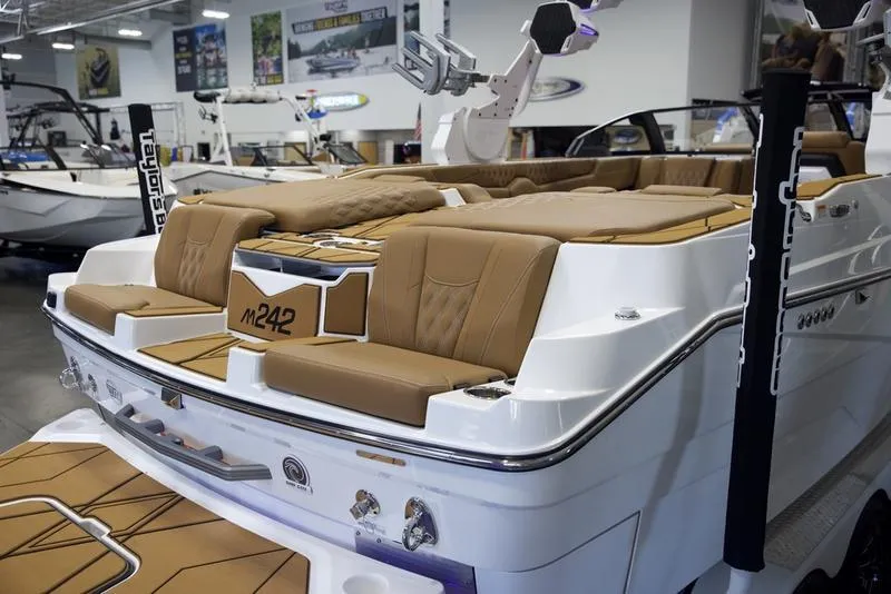Slide: The Image of 2025 Malibu M242 boat with luxurious tan seating in showroom. - 14