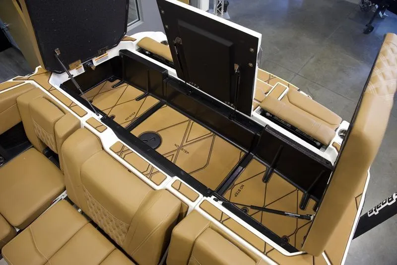 Slide: The Image of 2025 Malibu M242 boat interior storage compartments with tan seating. - 38