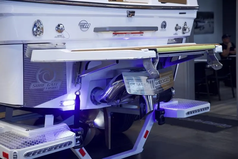 Slide: The Image of 2025 Malibu M242 boat rear view with advanced surf gate technology and illuminated platform. - 5