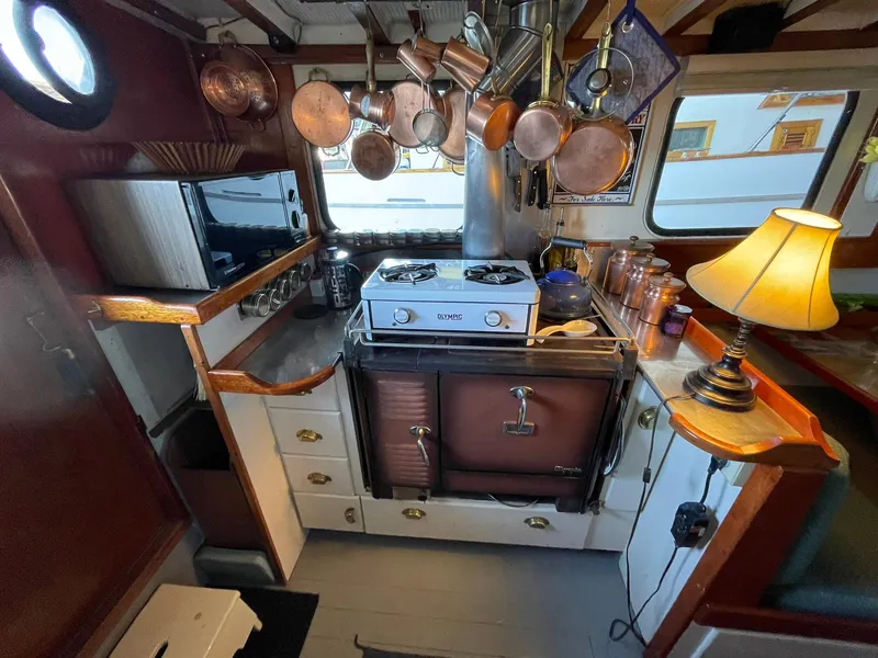 Slide: The Image of 1940 Historic Tacoma Boat Co Cruiser kitchen with stove, hanging pots, and cozy lamp. - 7