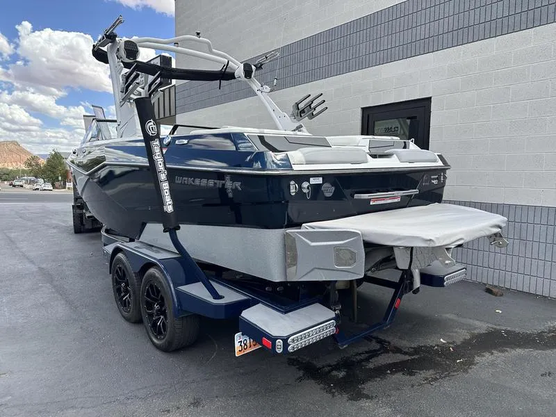 Slide: The Image of 2023 Malibu 22 LSV boat on trailer, parked near a building. - 11