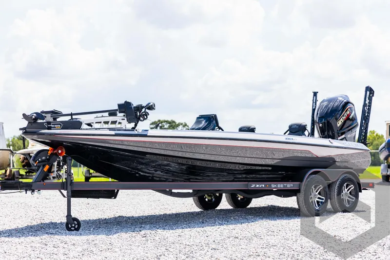 Slide: The Image of 2025 Skeeter ZXR 21 bass boat on trailer, black and silver design, parked outdoors. - 1