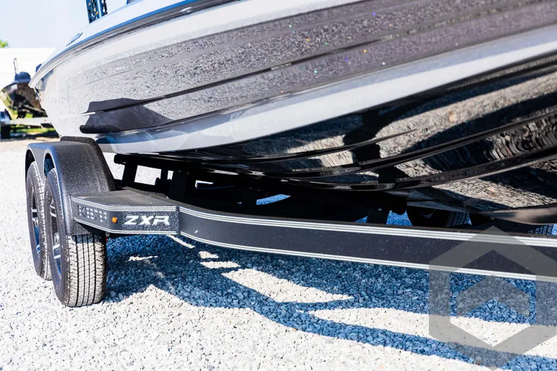 Slide: The Image of 2025 Skeeter ZXR 20 boat trailer, close-up view, parked on gravel. - 10