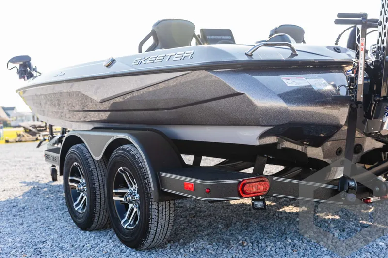 Slide: The Image of 2025 Skeeter ZXR 20 boat on trailer, sleek design, dual axles, parked on gravel. - 19
