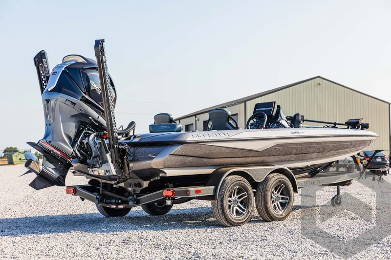 Slide: The Image of 2025 Skeeter ZXR 20 bass boat on trailer, parked on gravel near a building. - 5