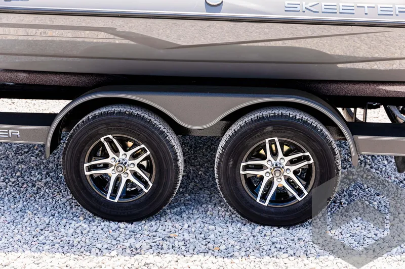 Slide: The Image of 2025 Skeeter ZXR 20 trailer wheels on gravel surface. - 23
