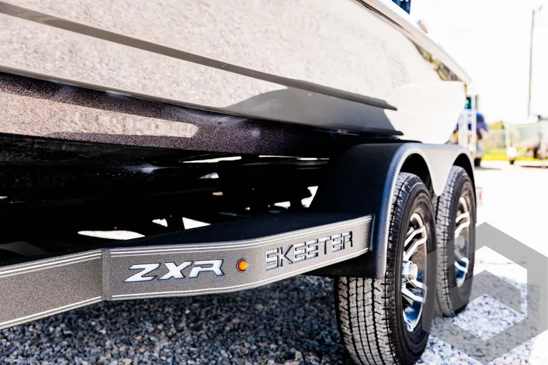 Slide: The Image of 2025 Skeeter ZXR 20 boat trailer with dual wheels on gravel. - 24