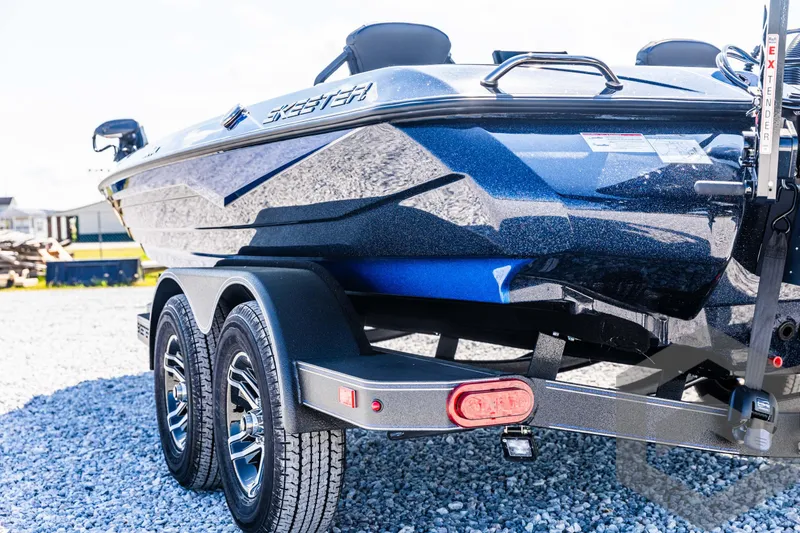 Slide: The Image of 2025 Skeeter ZXR 21 boat on trailer, metallic blue finish, parked on gravel. - 20