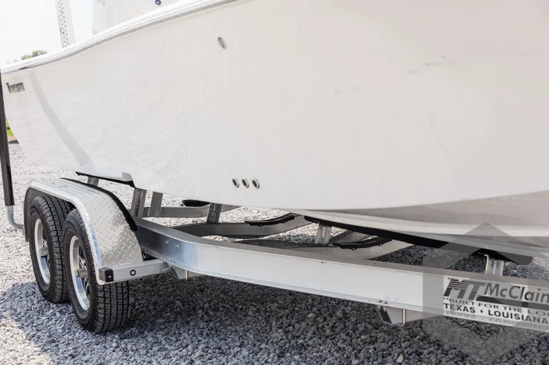 Slide: The Image of 2025 Tidewater 2300 Carolina Bay boat on a McClain trailer, parked on gravel. - 11