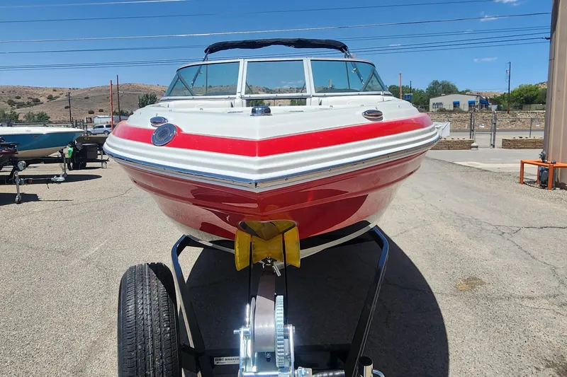 Slide: The Image of 2024 Crownline 210SS boat on trailer, red and white design, parked outdoors. - 3