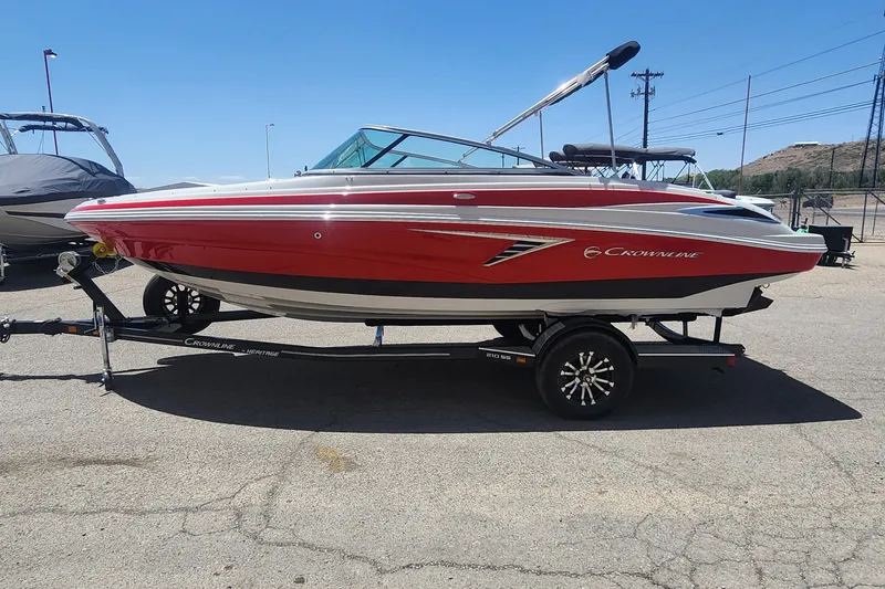 Slide: The Image of 2024 Crownline 210SS boat in red on a trailer, parked outdoors. - 5