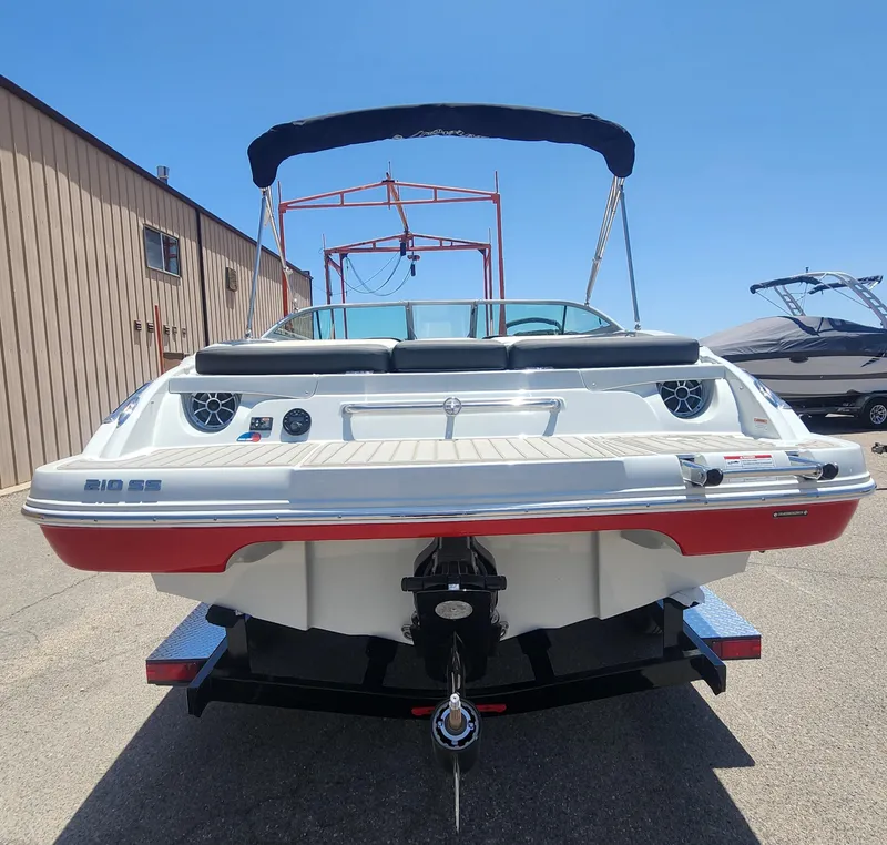 Slide: The Image of 2024 Crownline 210SS boat, rear view, parked outdoors under clear sky. - 6