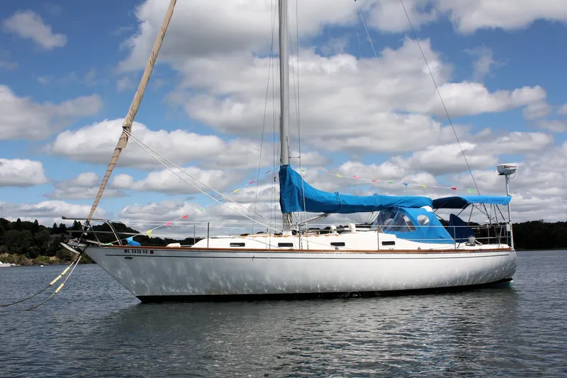 The Image of 1978 Tartan 37 sailboat with blue canopy on calm water under cloudy sky. - 0
