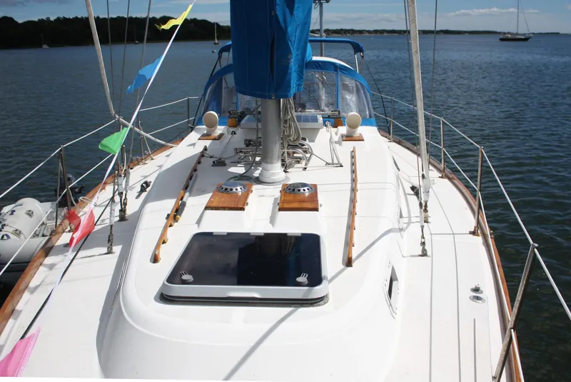 Slide: The Image of 1978 Tartan 37 sailboat deck with colorful flags, anchored on calm water. - 11