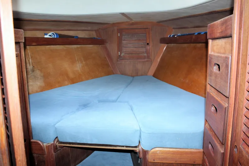 Slide: The Image of V-berth cabin interior of 1978 Tartan 37 sailboat with blue cushions and wooden cabinetry. - 22