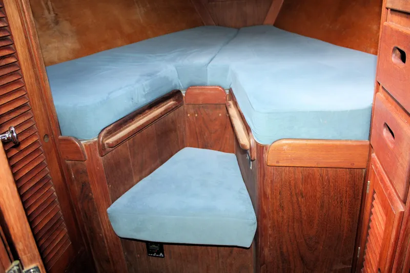 Slide: The Image of 1978 Tartan 37 sailboat interior with blue cushioned V-berth and wooden cabinetry. - 23