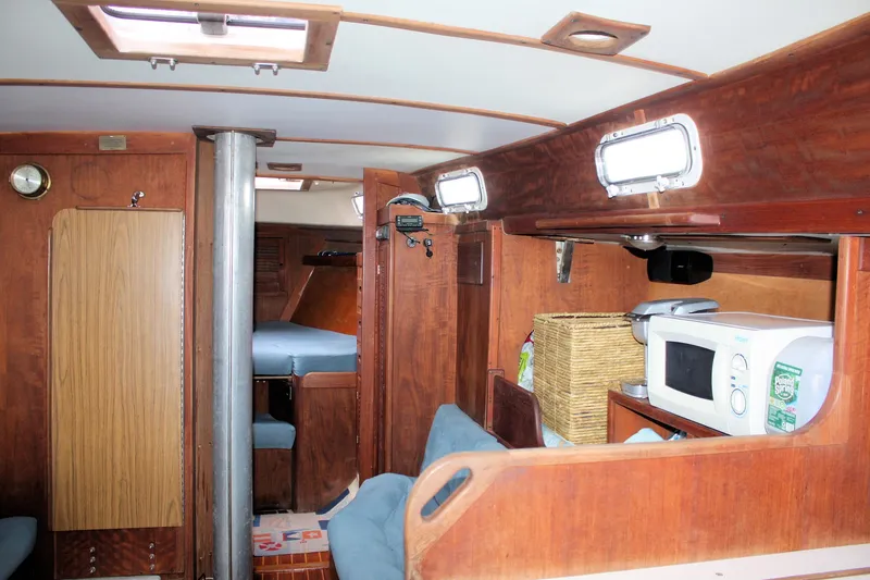Slide: The Image of 1978 Tartan 37 sailboat interior with wood finish, seating, and kitchenette featuring a microwave. - 24