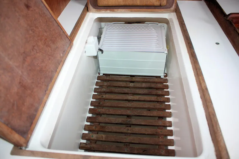 Slide: The Image of 1978 Tartan 37 boat interior storage compartment with wooden slats and cooling unit. - 34
