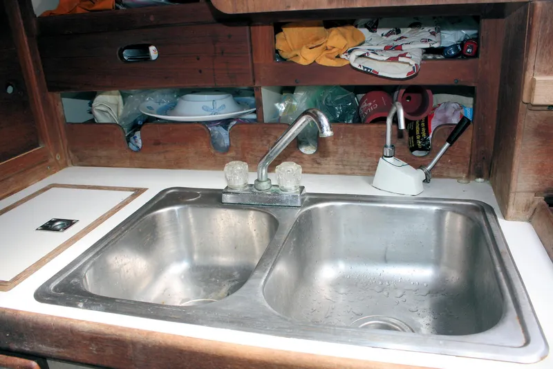 Slide: The Image of 1978 Tartan 37 yacht kitchen sink with dual basins and wooden storage shelves. - 36