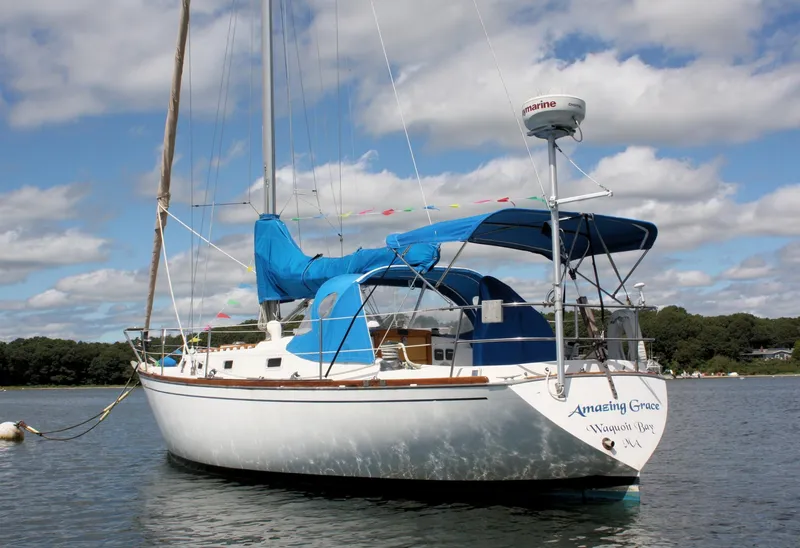 Slide: The Image of 1978 Tartan 37 sailboat with blue canopy, anchored on calm water under a cloudy sky. - 4
