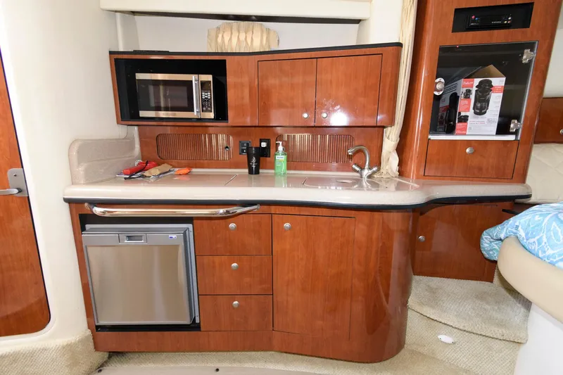 Slide: The Image of 2006 Sea Ray 320 Sundancer kitchen with wood cabinets, microwave, and sink. - 13