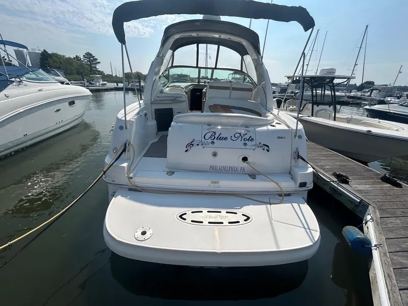 Slide: The Image of 2006 Sea Ray 320 Sundancer docked at marina, rear view with "Blue Note" name. - 2