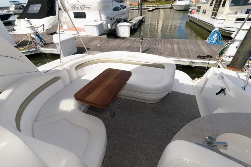 Slide: The Image of 2006 Sea Ray 320 Sundancer yacht with elegant seating and wooden table at marina. - 4