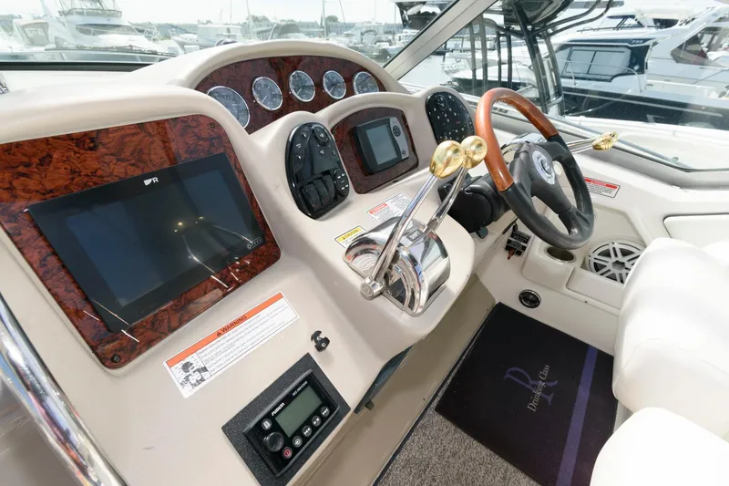 Slide: The Image of 2006 Sea Ray 320 Sundancer helm with modern controls and wood accents. - 7