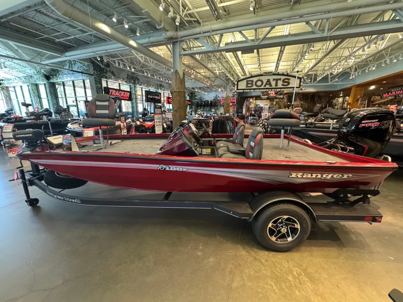 Slide: The Image of 2024 Ranger RT188P fishing boat displayed in showroom with red exterior and trailer. - 1
