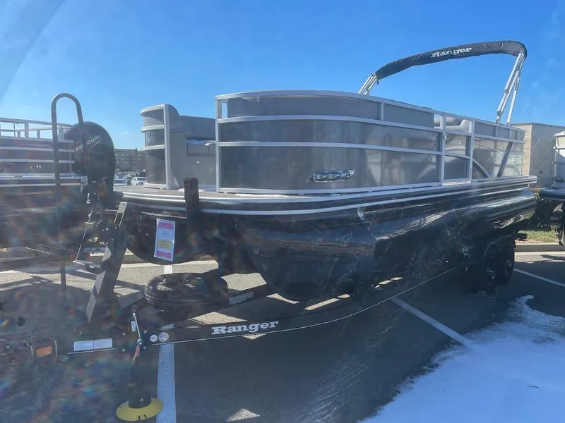The Image of 2024 Ranger Reata 223C pontoon boat on trailer, parked outdoors under clear blue sky. - 1