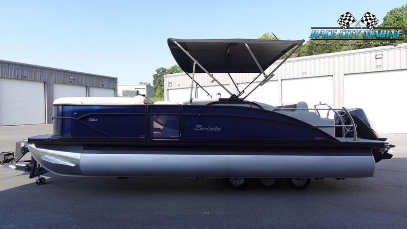 Slide: The Image of 2025 Barletta Cabrio 22U pontoon boat with canopy, parked outdoors. - 1