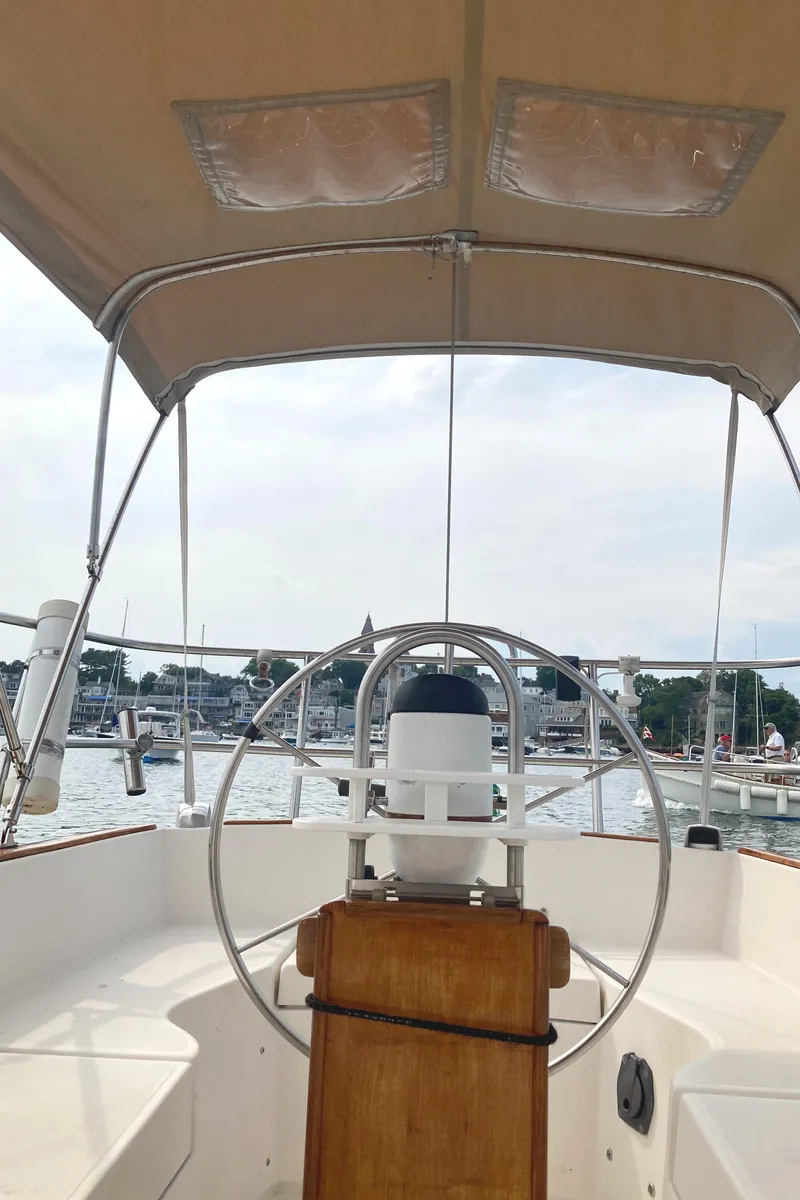 Slide: The Image of 1981 Sabre 34 sailboat cockpit with steering wheel, canopy, and marina view. - 13