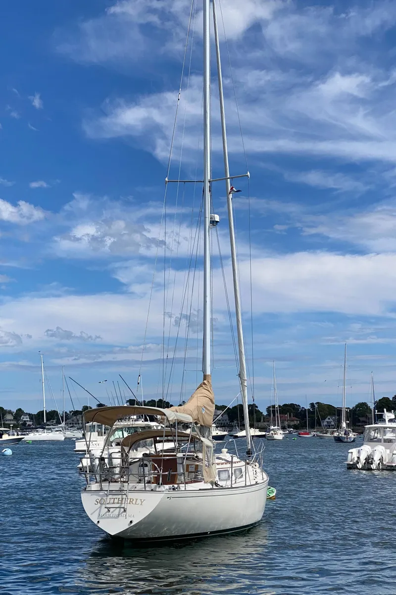 Slide: The Image of 1981 Sabre 34 sailboat anchored in a scenic harbor under a blue sky. - 2