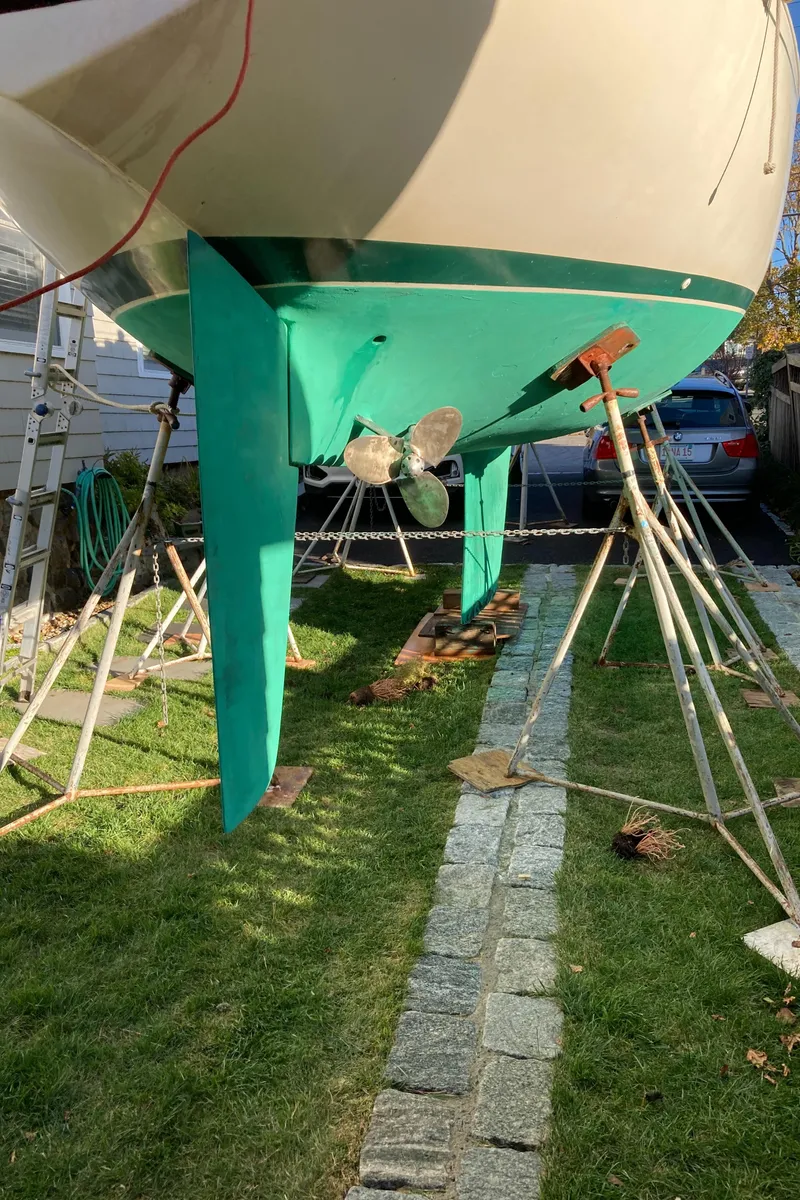 Slide: The Image of 1981 Sabre 34 sailboat on stands, showing keel and propeller, in a grassy yard. - 4