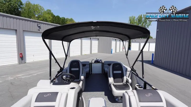 Slide: The Image of 2025 Barletta C24QC pontoon boat with canopy, parked near storage units. - 41