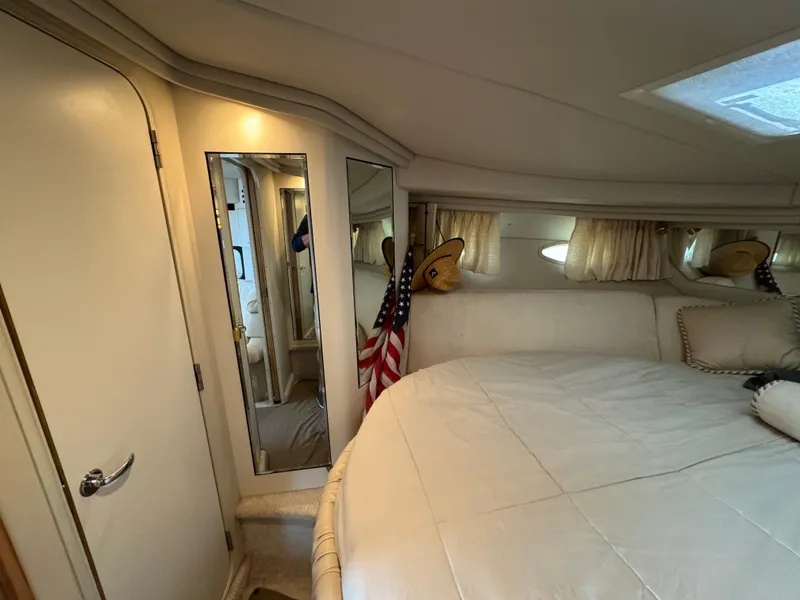 Slide: The Image of 1999 Sea Ray 380 Sundancer cabin interior with bed, mirror, and American flag. - 22