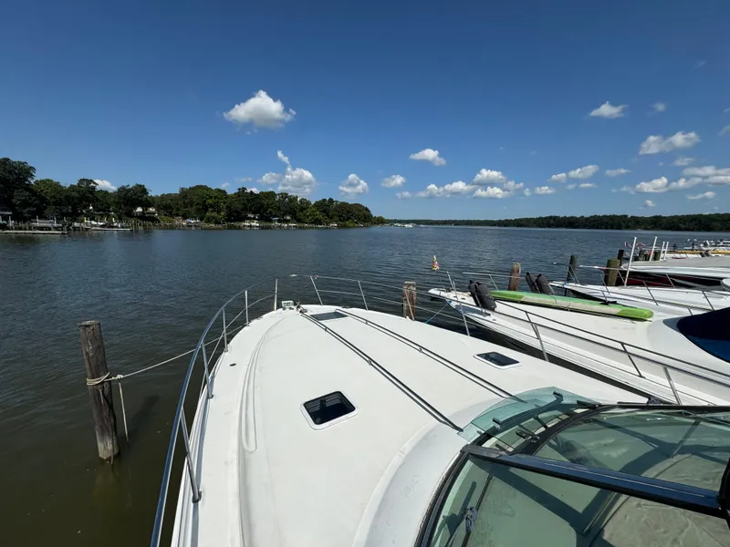 Slide: The Image of 1999 Sea Ray 380 Sundancer docked on a serene lake under a clear blue sky. - 3