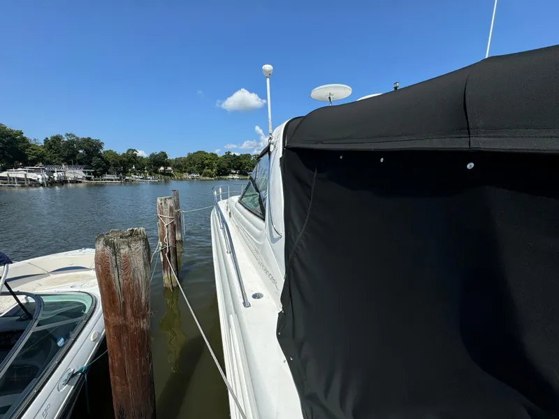 Slide: The Image of 1999 Sea Ray 380 Sundancer docked by a serene waterfront under a clear blue sky. - 6