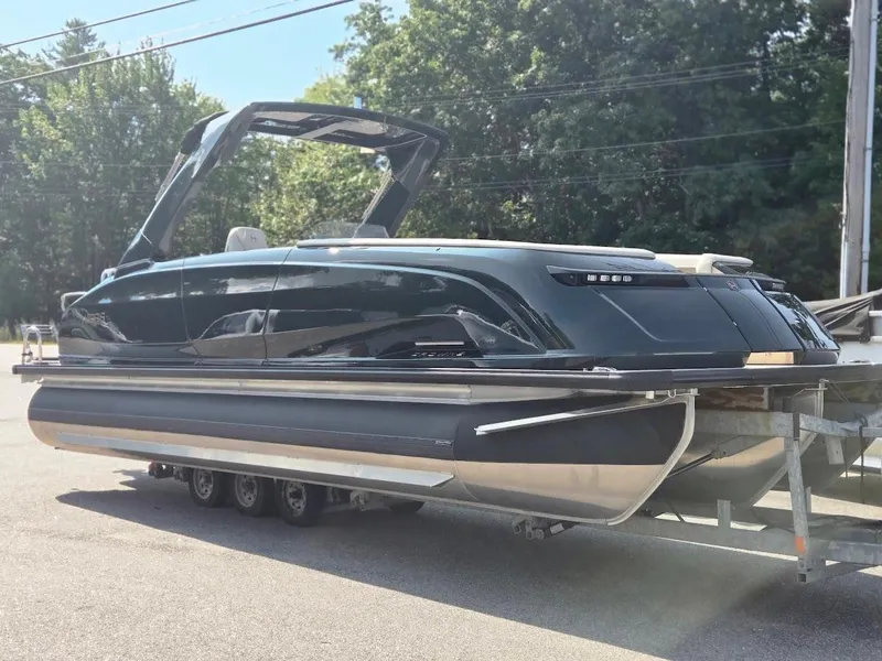 Slide: The Image of 2025 Harris Crowne SL 250 pontoon boat on trailer, parked outdoors. - 1