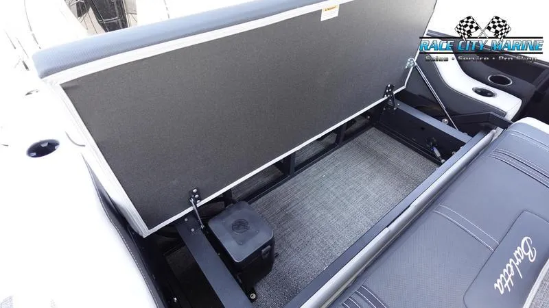 Slide: The Image of 2025 Barletta X23UC boat storage compartment with open seat and Race City Marine logo. - 17