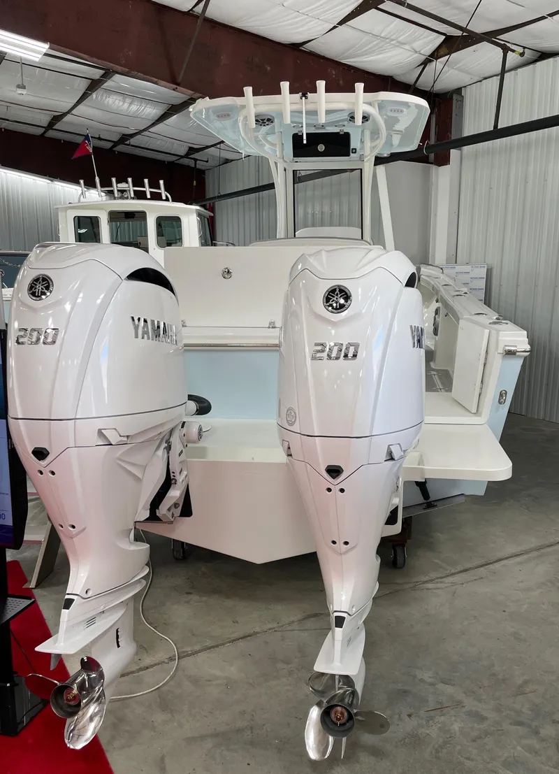 Slide: The Image of 2025 Parker 2600 Center Console boat with dual Yamaha 200 engines in a warehouse. - 2