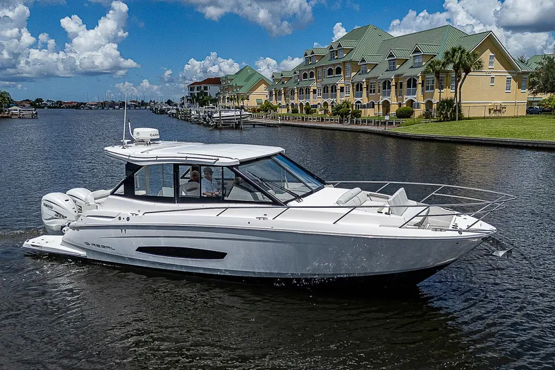Slide: The Image of 2022 Regal 36 XO yacht cruising on a scenic waterfront with luxury homes. - 48