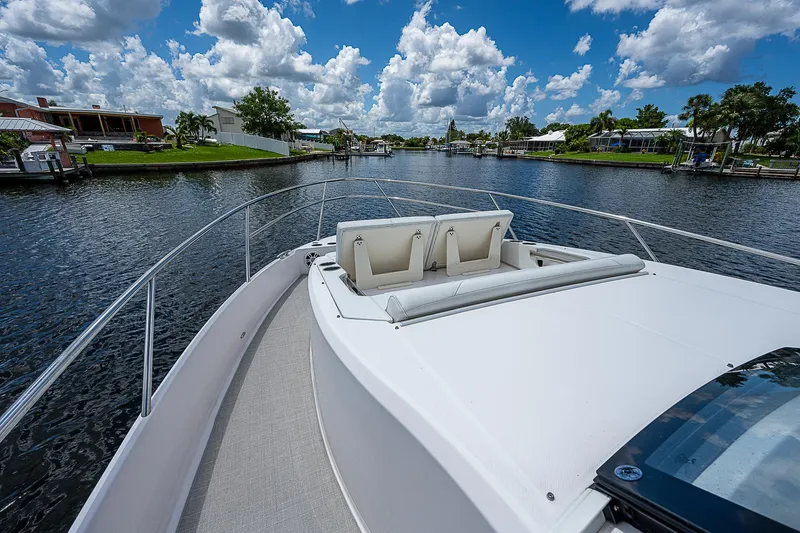 Slide: The Image of 2022 Regal 36 XO yacht cruising on a scenic river under a blue sky. - 5