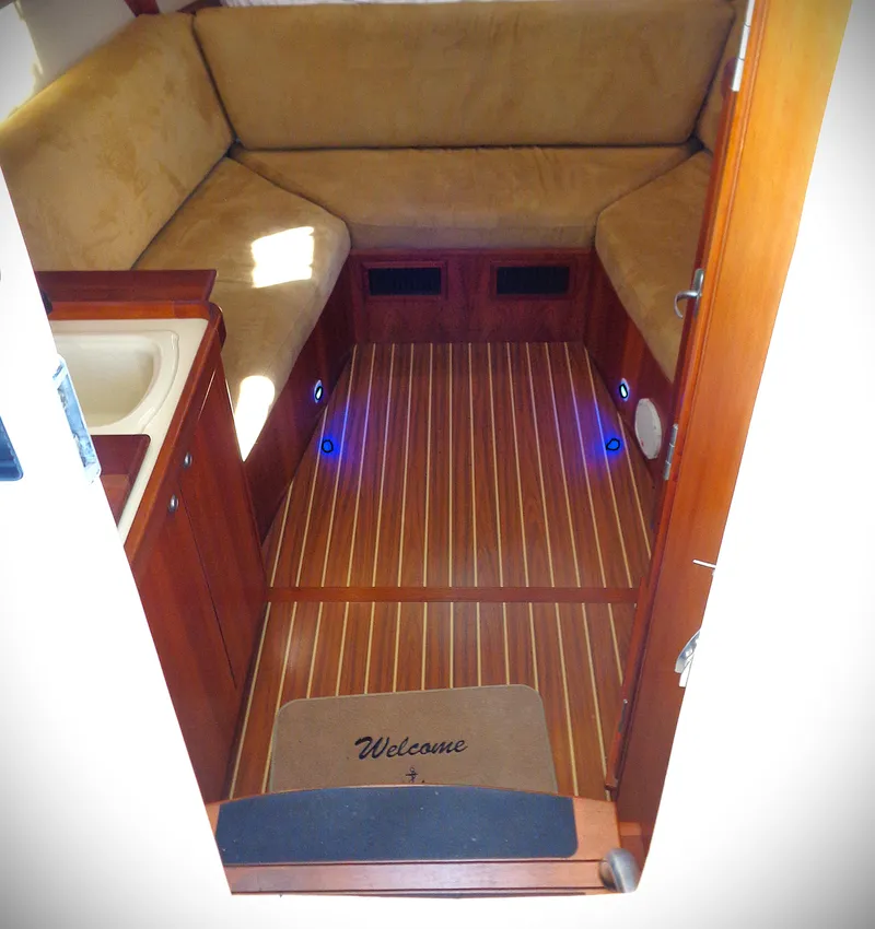 Slide: The Image of 2005 Mainship Pilot 30 Rum Runner II cabin with cozy seating and wooden flooring. - 1