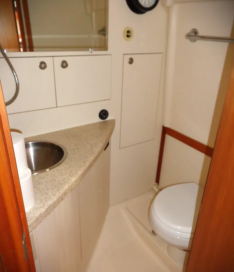 Slide: The Image of 2005 Mainship Pilot 30 Rum Runner II bathroom with sink, toilet, and storage cabinets. - 5