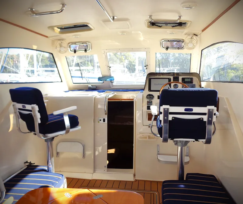 Slide: The Image of Interior of 2005 Mainship Pilot 30 Rum Runner II with blue seating and wooden flooring. - 7