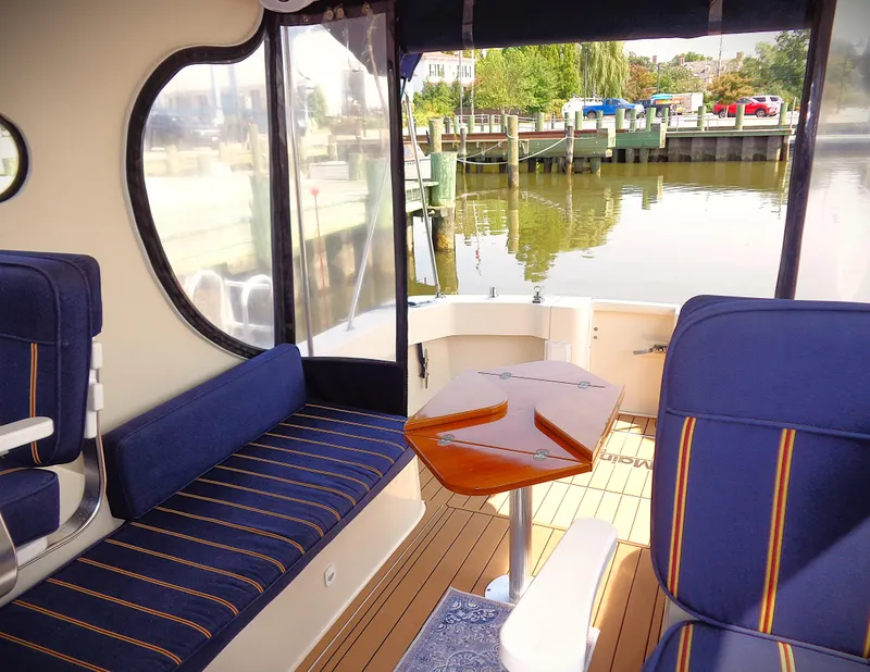 Slide: The Image of 2005 Mainship Pilot 30 Rum Runner II interior with blue seating and wooden table. - 8